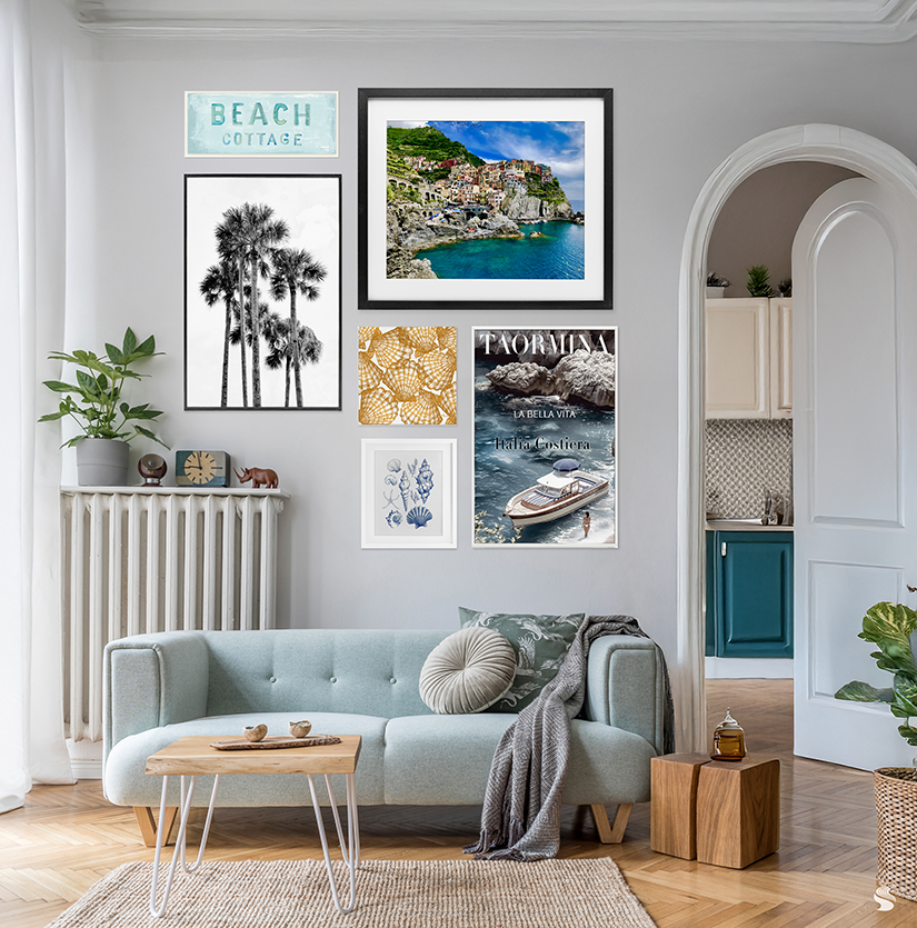 Modern coastal living room with soft blue sofa, wood coffee table, and a gallery wall featuring beach-themed art prints.