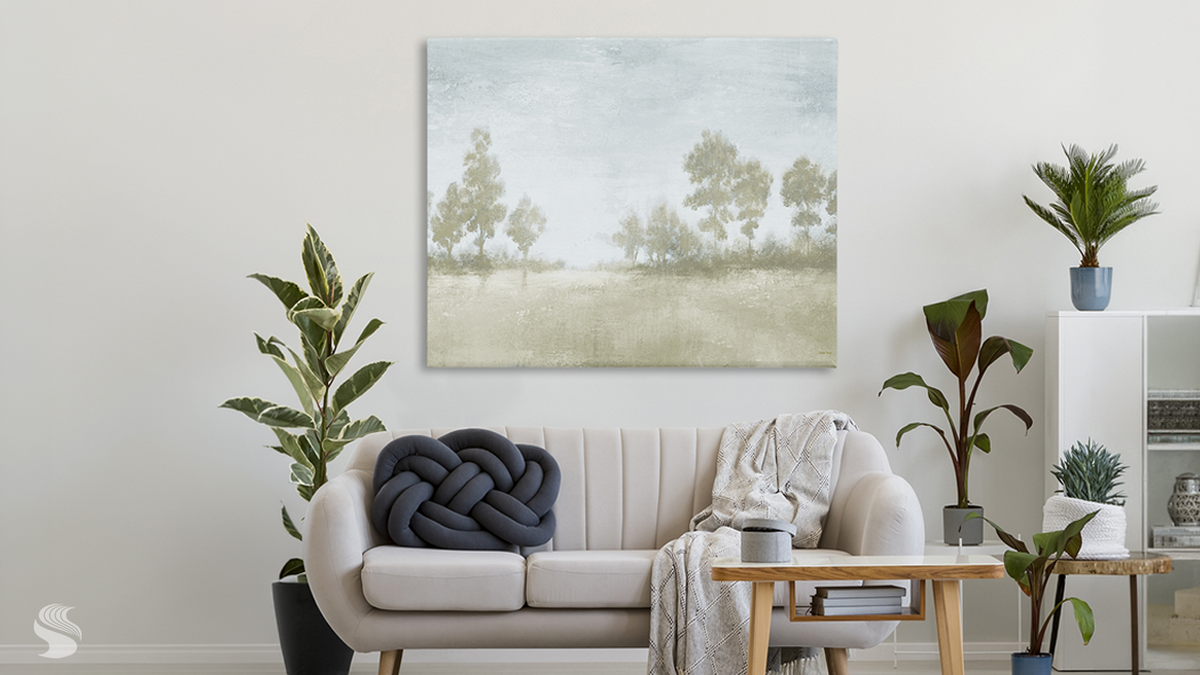 Soft green landscape canvas above a cream sofa in a neutral living room.