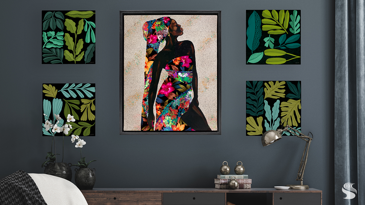 Modern living room gallery wall featuring a vibrant portrait of a woman in floral textiles surrounded by botanical leaf prints on a deep blue wall, styled above a walnut console to celebrate contemporary Black artists.