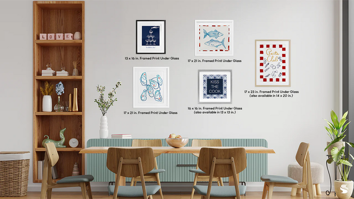 Modern dining room with wood furniture and a gallery wall of framed print-under-glass art in various sizes and styles.